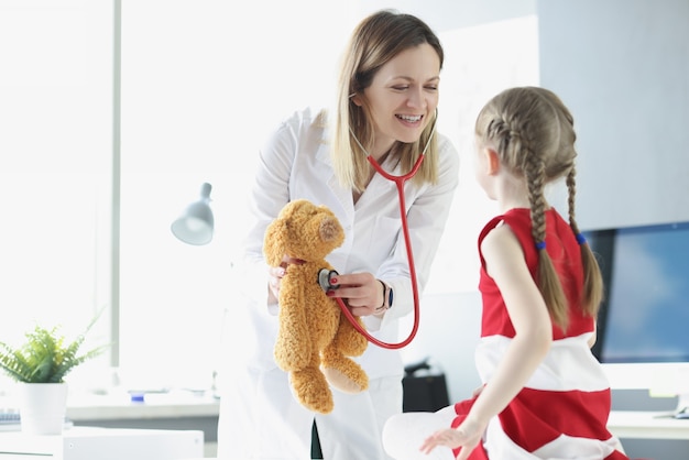 Un pédiatre montre à une petite fille comment utiliser un stéthoscope en utilisant un jouet comme pédiatre par exemple