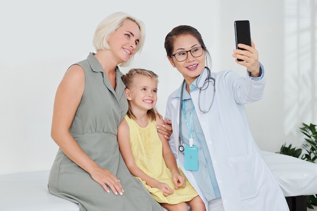 Pédiatre prenant selfie avec patient et sa mère