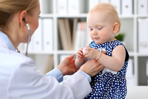 Le pédiatre prend soin de bébé à l'hôpital. Une petite fille est examinée par un médecin avec un stéthoscope. Concept de soins de santé, d'assurance et d'aide.