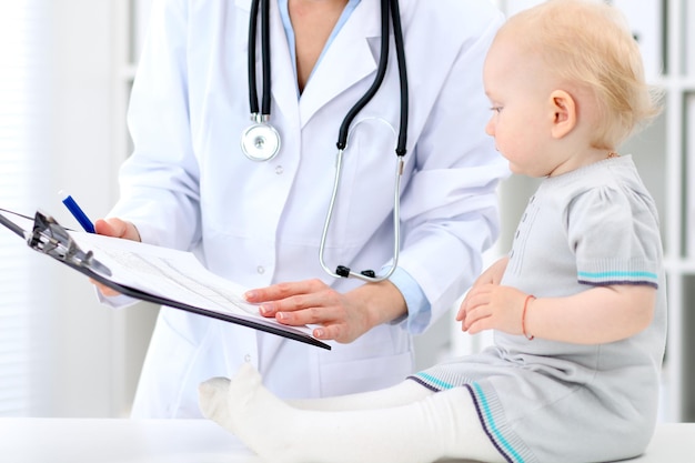 Le pédiatre prend soin de bébé à l'hôpital. Une petite fille est examinée par un médecin avec un stéthoscope. Concept de soins de santé, d'assurance et d'aide.