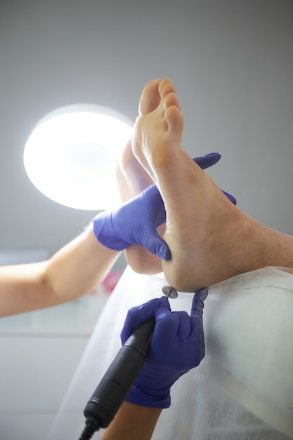 Peeling pieds Pédicure SPA procédure dans le salon de beauté. Appareil électrique pour pédicure. Femme se faire éplucher les pieds dans un centre de spa