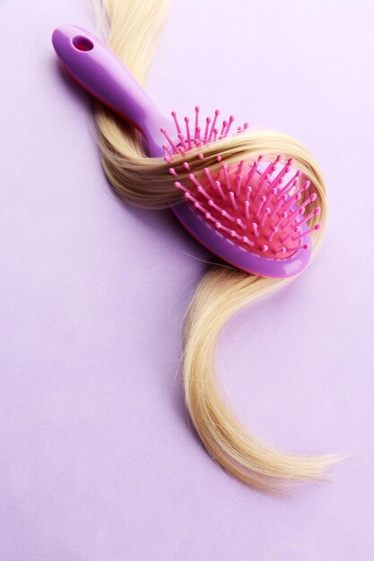 Peigne brosse avec des cheveux sur fond violet