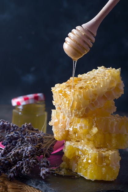 Peigne de miel avec des fleurs de lavande - aliments sucrés sur fond sombre