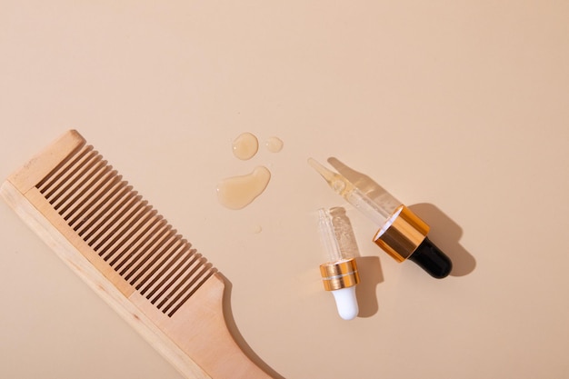 Peigne et pipettes avec de l'huile ou des vitamines pour le concept de soins capillaires