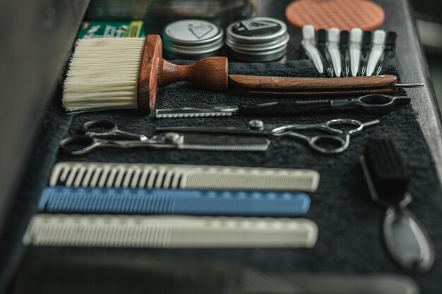 Peignes ciseaux et brosses placés sur une serviette noire sur la table en salon de coiffure