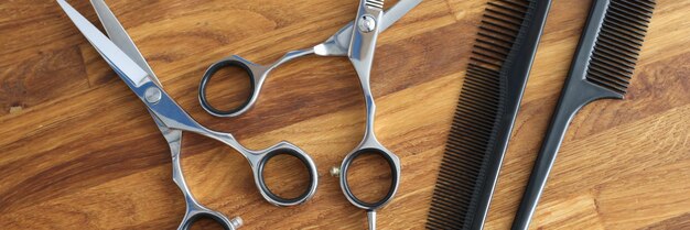 Peignes de coiffeur et ciseaux métalliques allongés sur une table en bois agrandi