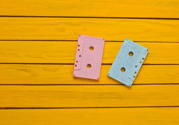 Peint dans une cassette audio couleur rose bleu pastel sur un fond en bois jaune. Technologie audio rétro.