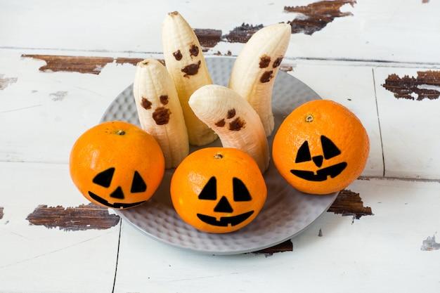 Photo peint de drôles de visages sur les mandarines et les bananes pour halloween