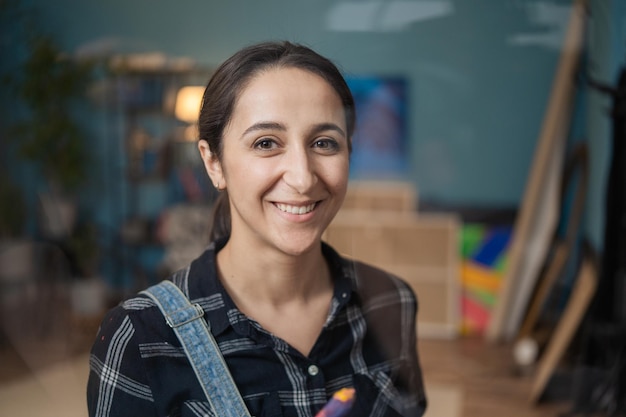 Peintre aux yeux bruns aux cheveux noirs regardant la caméra avec un sourire