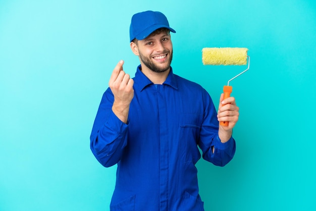 Peintre caucasien homme isolé sur fond bleu faisant un geste d'argent