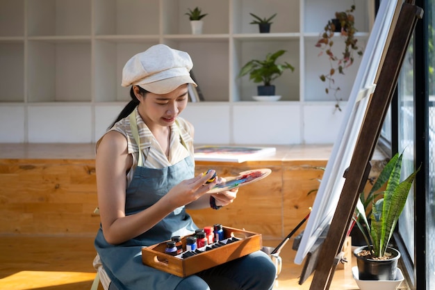 Peintre de femme asiatique positive peignant dans son atelier.