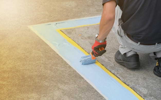 Un peintre peint des lignes bleues de stationnement dans un parking