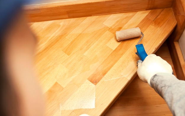 Photo le peintre peint une planche de bois vernis au rouleau