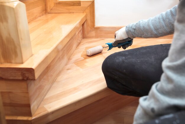 Photo le peintre peint une planche de bois vernis au rouleau