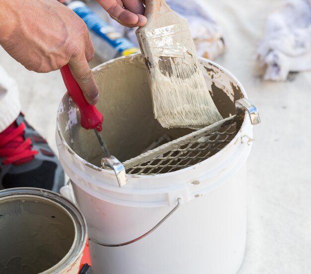 Peintre professionnel chargeant de la peinture sur son pinceau à partir d'un seau