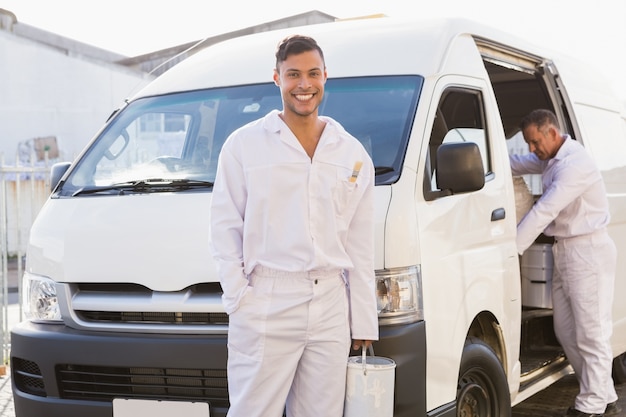 Peintre souriant appuyé contre sa camionnette