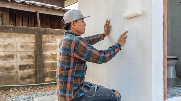 Le peintre travaille à peindre les murs blancs de la salle de bain