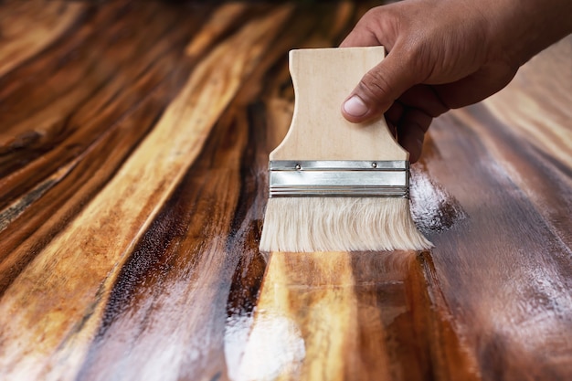 Peintre utilise des parcelles de peinture pour enduire le bois pour la beauté.