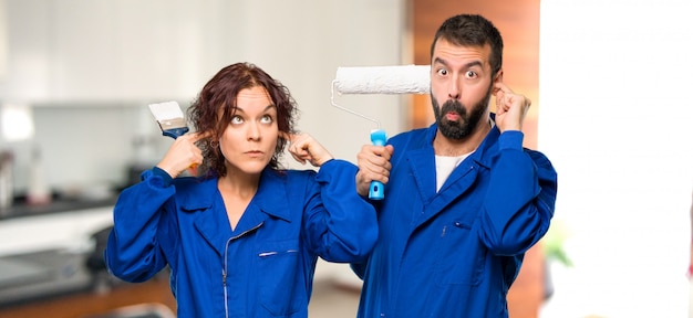 Peintres couvrant les oreilles avec les mains dans la maison