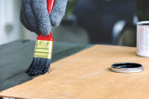 Photo les peintres travaillent mettre un gant et peint sur une planche de bois posée sur un plancher en bois