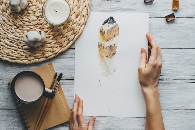 Peinture à l'aquarelle avec pinceau et tasse de café sur la texture en bois.