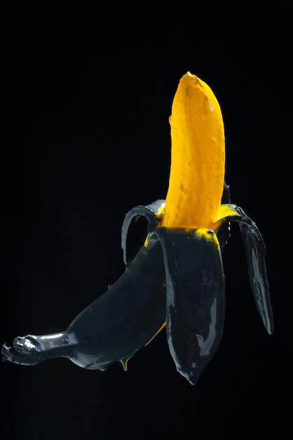 Peinture à la banane. Banane peinte en jaune-noir sur fond noir en lévitation