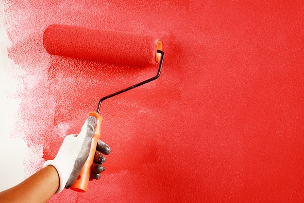 Peinture à la brosse à rouleau, peinture d'ouvrier sur le mur de surface Appartement de peinture, à rénover avec de la peinture de couleur rouge.