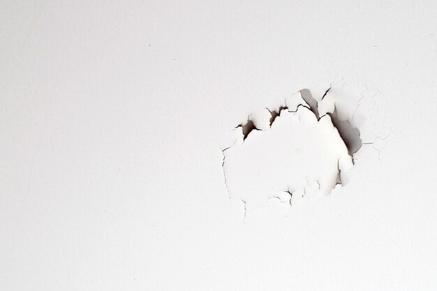 Peinture de couleur blanche qui se décolle sur le plafond de la maison. Sous le toit