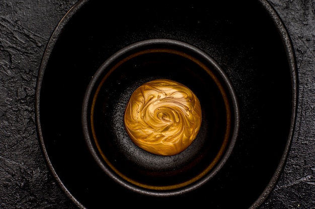 Peinture dorée fondue dans un bol noir