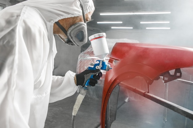 Peinture finale de pièces de carrosserie de voiture dans la chambre de peinture et de vernis après les travaux de réparation de la carrosserie du véhicule