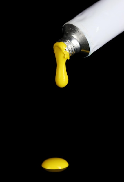 La peinture jaune suit le tube sur fond noir en gros plan