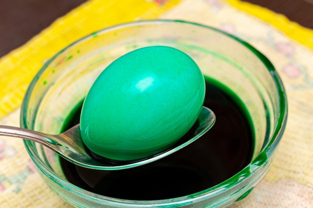 Peinture d'oeufs verts mourants pour Pâques dans un bocal en verre avec une cuillère