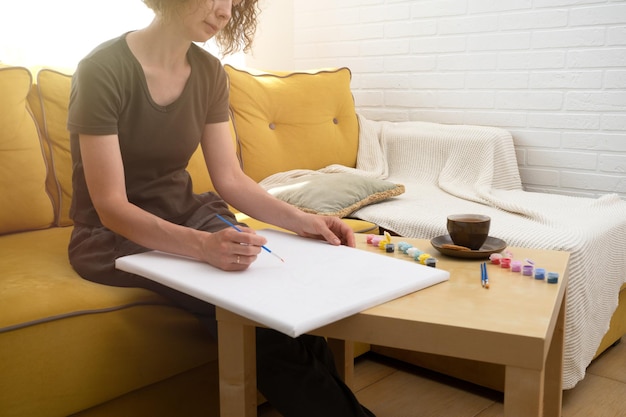 Peinture pour débutants Jeune femme dessinant une image par numéros avec des peintures acryliques sur toile profitant d'activités de loisirs créatives