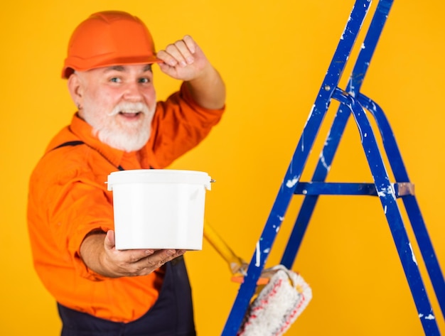 Peinture et rénovation de maison Entreprise faisant l'outil de réparation Peintre travaillant sur le chantier de construction homme âgé utilisant un rouleau sur une échelle dans l'appartement