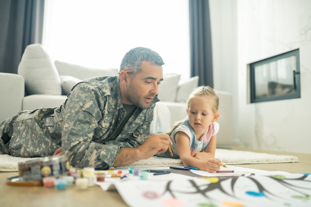 Peinture avec sa fille. Bel homme militaire mature peignant l'arbre généalogique avec sa fille mignonne