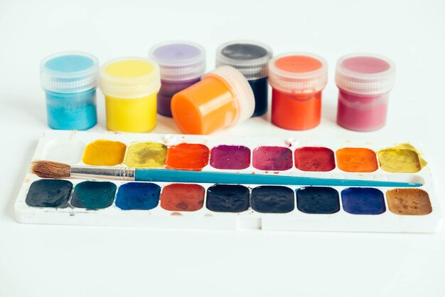 Peintures gouache colorées et pinceau pour peindre sur une table en bois blanc. Copie, espace vide pour le texte