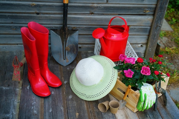 Photo pelle arrosoir chapeau bottes en caoutchouc fleurs gants et outils de jardin