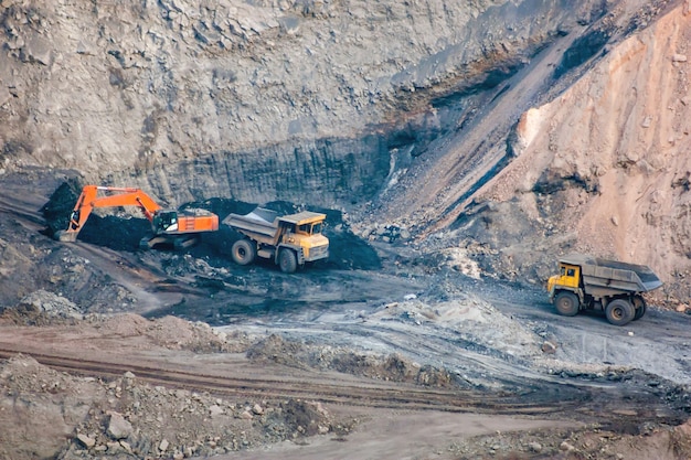 La pelle sur chenilles et les camions à benne basculante travaillent dans une carrière