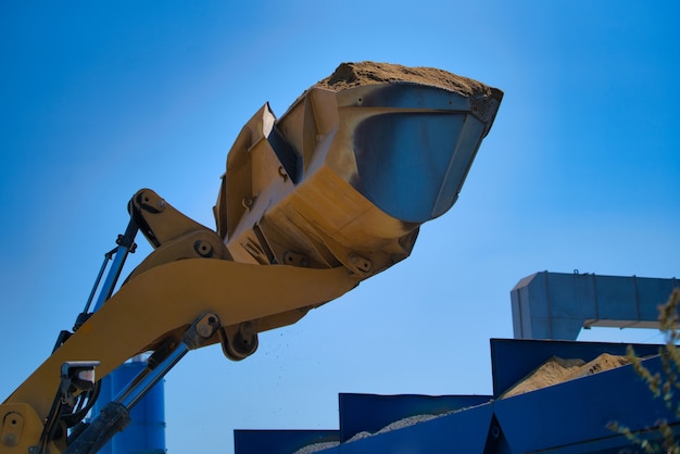 Photo pelle jaune sur un chantier de construction contre le ciel bleu.