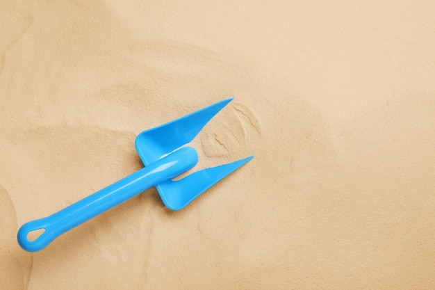 Pelle à jouet en plastique brillant sur la vue de dessus de sable