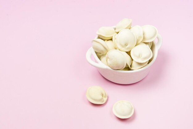 Pelmeni russes non cuits dans un bol blanc Pelmeni fait maison raviolis ou boulettes avec espace de copie horizontal de viande