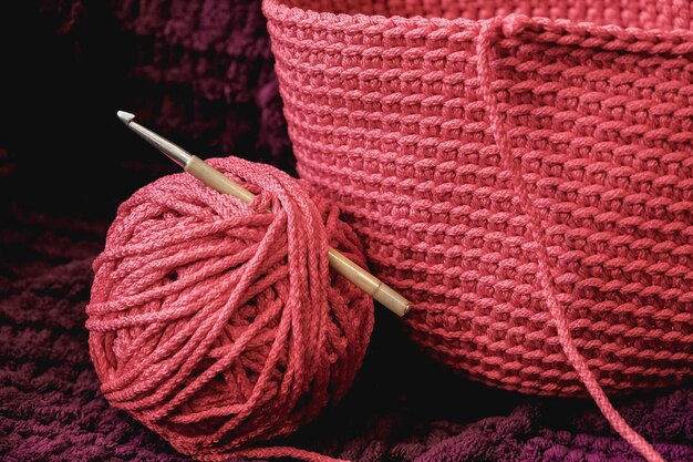 Pelote de fil rose avec une aiguille et un tissu tricoté sur fond de matière violette
