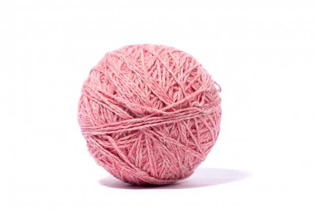 Pelote de fil rose en laine isolé sur mur blanc.