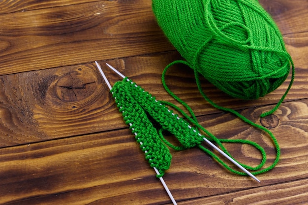 Pelote de laine et aiguilles à tricoter avec tricot sur table en bois