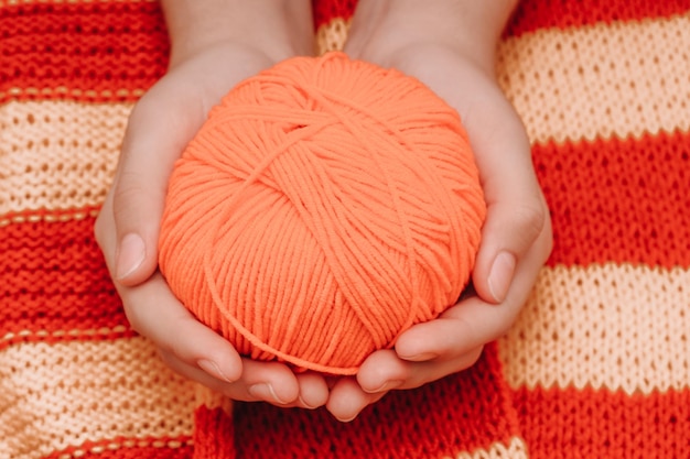 Pelote de laine rouge dans les mains sur une nappe rouge jaune