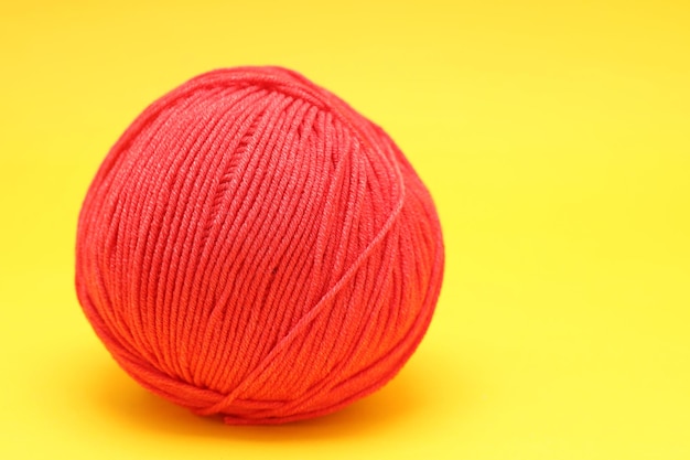 La pelote de laine rouge se trouve sur un fond jaune. photo de haute qualité
