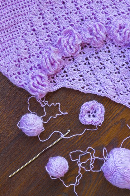 Pelote de laine violette, crochet et veste tricotée sur table