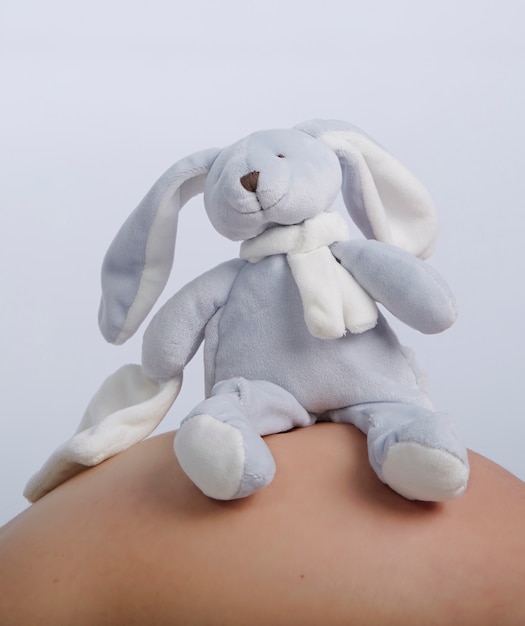 Peluche bébé sur un ventre de femme enceinte