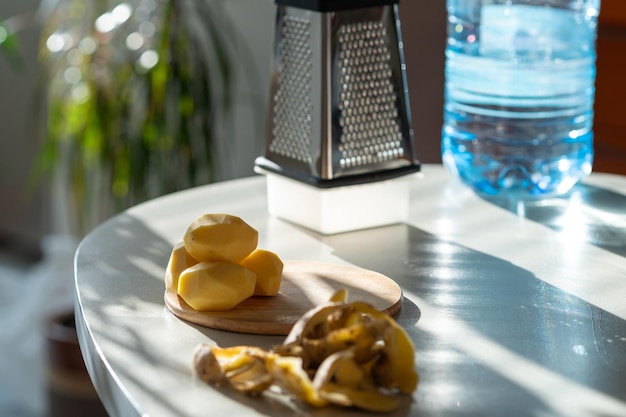 Photo les pelures de pommes de terre et les pommes de terre épluchées se trouvent sur la table de la cuisine