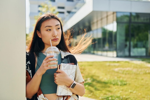 Penché sur le mur Jeune femme asiatique est à l'extérieur pendant la journée